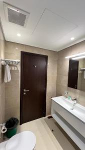 塞拉莱Hawana salalah Apartment Mimosa的一间带卫生间、水槽和棕色门的浴室