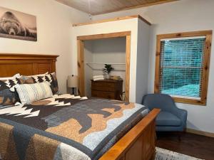 布赖森城Nantahala Nook, cabin w/hot tub,game room, & wifi的卧室配有床、椅子和窗户。