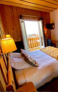Le Sappey-en-Chartreuse德斯科耶酒店的一间卧室配有一张带窗户和灯的床