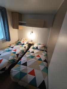 阿旺桥mobil home 3 chambres 152的一间卧室配有两张床和五颜六色的被子