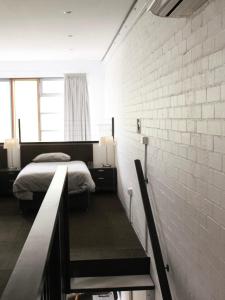 NarrabundahLarge Bright Modern Loft Apt - Central Location - Suitable for Families and Groups的一间卧室设有两张床和砖墙