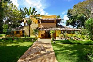 托兰克索Casa Baiana Pousada & Aconchego的一座带棕榈树绿色庭院的房子