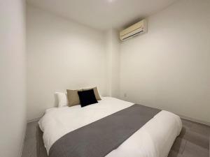 ŌsukachōbHOTEL Nikke - Apt for 10Ppl Ideal for Big Group in City Center的卧室配有一张带黑色枕头的白色床