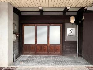 高山Hostel Miyagawa by Murasaki Ryokan的建筑物的门,上面有标志