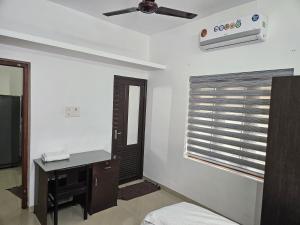 科泽科德Saaketh Holiday Home的一间卧室配有书桌和带吊扇的窗户。