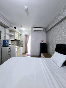 雅加达Apt Bassura Studio Tower F w/ Pool, Wi-Fi & Netflx的一间带白色大床的卧室和一间厨房