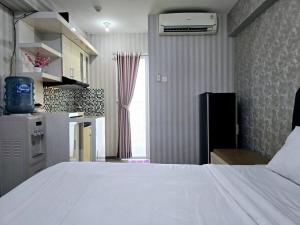 雅加达Apt Bassura Studio Tower F w/ Pool, Wi-Fi & Netflx的一间带白色床的卧室和一间厨房