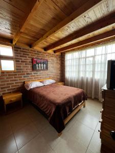 奥塔瓦洛Cabañas Tecla María的卧室设有一张砖墙内的大床
