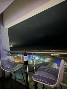 利马Departamento con vista al mar的一张玻璃桌,配有一瓶葡萄酒和两把椅子