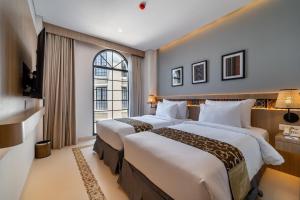 龙目岛库塔MONTANA @OCEANSIDE MANDALIKA的配有窗户的酒店客房内的两张床