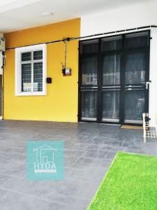 Kampong TengahHYDA Homestay Melaka, Durian Tunggal的黄色的建筑,有黑色的门和院子