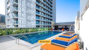 迪拜温德姆迪拜码头酒店的一座游泳池,旁边设有橙色和蓝色的躺椅