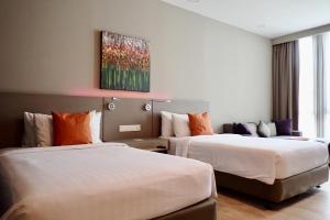 八打灵再也Qliq Damansara Hotel的酒店客房设有两张床,墙上挂有绘画作品