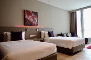 八打灵再也Qliq Damansara Hotel的酒店客房设有两张床,墙上挂有绘画作品