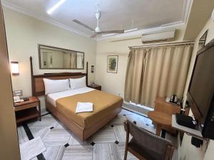 孟买船坞帝都酒店的一间卧室配有一张床、一张书桌和一台电视
