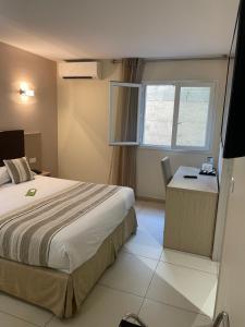 博尼法乔阿马多内塔酒店的配有一张床、一张书桌和一扇窗户的酒店客房