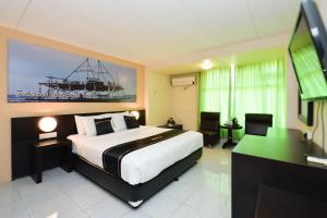丹戎槟榔OYO 2487 Sampurna Jaya Hotel的一间卧室配有一张床、一张书桌和一台电视