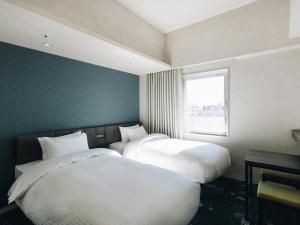 宫崎Prince Smart Inn Miyazaki的带窗户的客房内的两张床