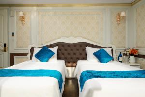下龙湾La Renta Premium Cruise的两张位于酒店客房的床,配有蓝色枕头