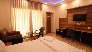 曼达莫尼Sea Queen Beach Resort On Beach的酒店客房配有一张床、一张书桌和一台电视。