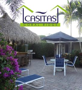 劳德代尔堡Casitas Coral Ridge的庭院配有桌椅和遮阳伞。