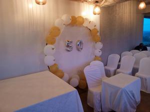 基加利ALLY NGALI MOTEL的一间设有白色桌子、白色椅子和气球的房间