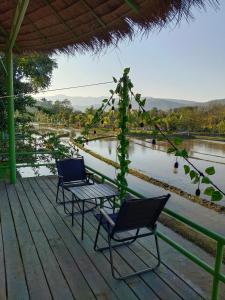 琅勃拉邦Glamping Laos的河边甲板上的两把椅子和一张桌子