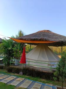 琅勃拉邦Glamping Laos的一个带稻草屋顶和红伞的帐篷