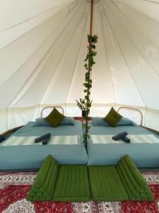 琅勃拉邦Glamping Laos的帆布帐篷内的一张床位,配有绿色枕头