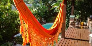 巴拉奈里奥-坎布里乌Quarto na Praia de Taquaras的悬挂在门廊上的橙色吊床,带游泳池