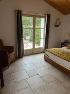 Le Grand VieilChambres d'hôtes LES CHENES VERTS的一间卧室设有一张床和一个滑动玻璃门