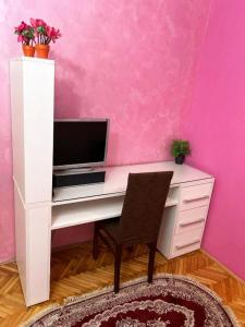 波德戈里察Villa Old Town的一张白色的桌子,上面有电脑,放在粉红色的墙上