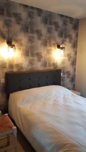 蒂耶扎克Le Castel du Cantal Groupe Village Fani的卧室配有白色床,墙上有两盏灯