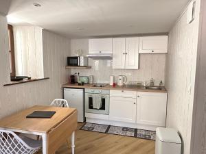 凯泽贝尔Duplex en ville vue château - Studio - Parking的厨房配有白色橱柜和木桌
