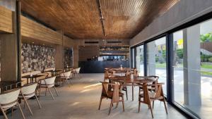 蔻立Casa De La Flora - SHA Extra Plus的餐厅设有木桌、椅子和窗户。