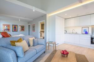 剑桥Luxury City Centre Apartment - Stunning Water View的一间带蓝色沙发的客厅和一间厨房