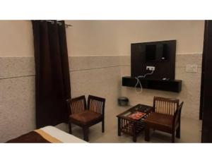 PānīpatHotel Park Blu, panipat的一间卧室配有两把椅子、一张桌子和一台电视。