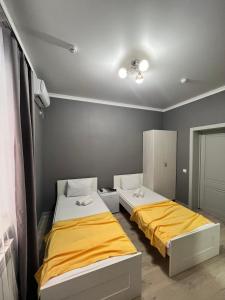 阿克托比Мини-гостиница Береке的黄色和灰色墙壁的客房内的两张床