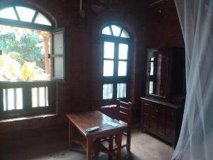 甘帕普拉Konkan Nest Resort的客房设有木桌和2扇窗户。