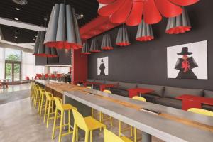 迈阿密Radisson RED Miami Airport的餐厅设有长长的酒吧,配有黄色和红色的椅子