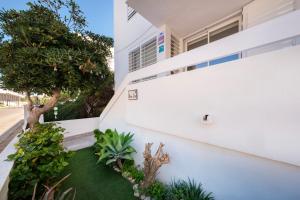 科洛尼亚圣霍尔迪Alma Libre Beach Apartment的享有白色房屋和小花园的外部景色