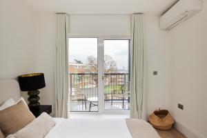 伦敦The Wembley Park Sanctuary - Stunning 2BDR Flat with Balcony的一间卧室设有一张床和一个滑动玻璃门