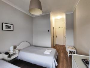 布拉加阿威尼达布拉格斯商业酒店的一间小卧室,配有白色的床和走廊