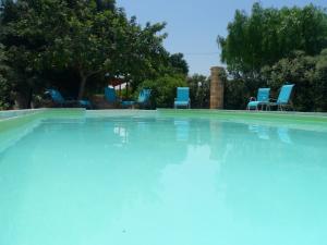 奥斯图尼Masseria Pugliese Farm的一个带蓝色椅子和树木的大型游泳池