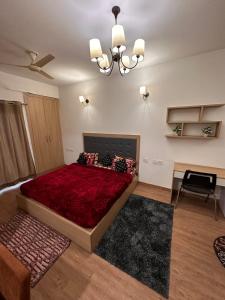 诺伊达Palm Studio & looms的一间卧室配有一张红色大床和吊灯