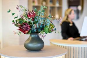 欧登塞欧登塞酒店的和女人一起在桌子上放着鲜花的绿色花瓶