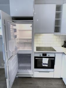 奥斯陆比斯尔特康伯尼公寓的白色的厨房配有开放式冰箱和烤箱