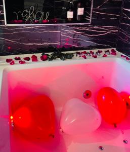 马拉科夫Relax Room proche PARIS Porte de Versailles的粉红色的浴缸,有红色的气球和玫瑰