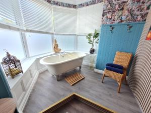 伯恩茅斯Lemur Lodge - Boutique Apartments - Short Stroll to The Beach的一间带白色浴缸和椅子的浴室