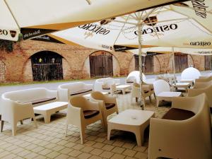 奥西耶克Hi Hostel Stara Pekara Osijek的一间设有白色桌椅和遮阳伞的餐厅